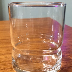 Op de afbeelding: Een helder glazen tumbler met een dikke bodem. Het glas is cilindrisch en heeft een gladde, gepolijste afwerking.