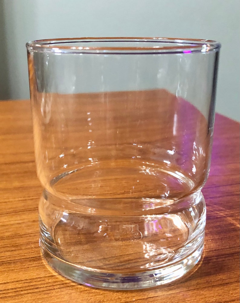 Op de afbeelding: Een helder glazen tumbler met een dikke bodem. Het glas is cilindrisch en heeft een gladde, gepolijste afwerking.