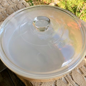 May include: A white glass casserole dish with a clear glass lid. The lid has a knob on top.