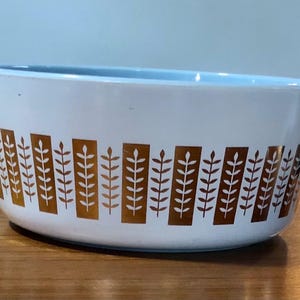 May include: White ceramic baking dish with a blue rim and a gold leaf pattern around the edge.