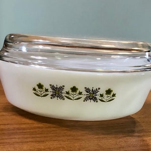May include: White oval casserole dish with a clear glass lid. The dish has a green and black floral design around the edge.