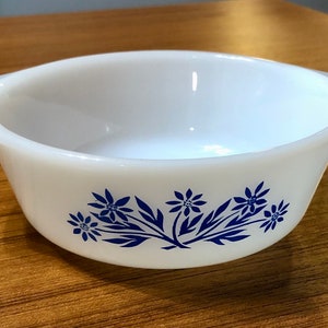 May include: White ceramic baking dish with blue floral design. The dish has two handles on the sides.