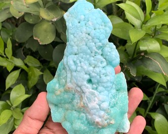 May include: A large, light blue, bubbly, and textured mineral specimen. The mineral has a white, cloudy center and a light blue, bubbly exterior.