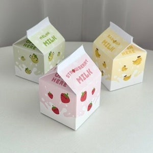 May include: Three miniature milk carton boxes with different flavors: melon, strawberry, and banana. Each box has a cute cartoon illustration of the corresponding fruit and the text "Milk" on the front.