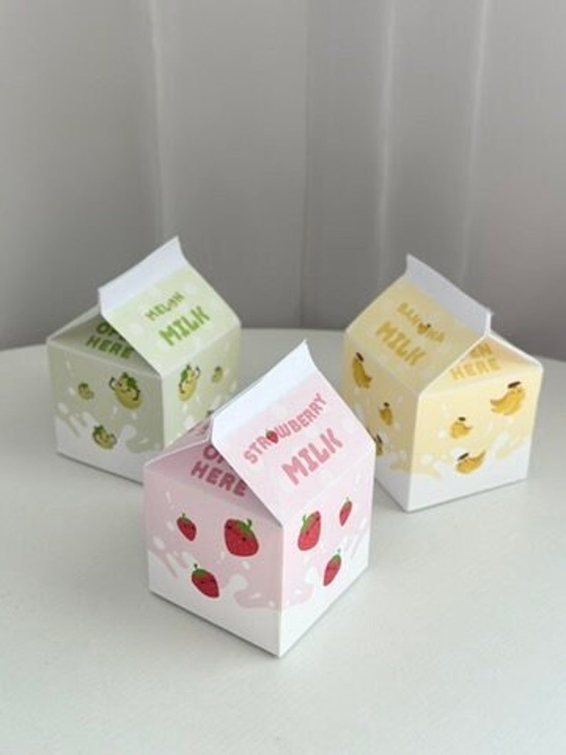 May include: Three miniature milk carton boxes with different flavors: melon, strawberry, and banana. Each box has a cute cartoon illustration of the corresponding fruit and the text "Milk" on the front.