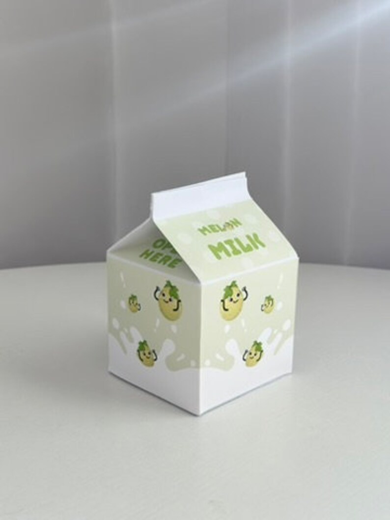 May include: A white cardboard box shaped like a milk carton with a green and white design. The box has a cartoon melon on it and the words "MELON MILK" printed on the front.