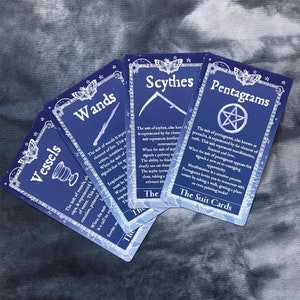 May include: A set of tarot cards with blue backgrounds and white text. The cards are arranged in a fan shape, with the top card showing the suit of pentagrams. The text on the card reads "The suit of pentagrams, also known as pentacles, is represented by the element of earth. This suit represents manifestation, abundance and love."
