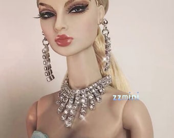 May include: A doll with blonde hair and dramatic makeup, wearing a sparkling rhinestone necklace and matching earrings. The doll is also wearing a light blue dress. The image includes the text "SHIP DIRECTLY FROM USA".