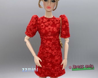 May include: Red floral print dress with puffed sleeves for a doll. The dress is short and has a fitted silhouette. The doll is wearing a gold chain strap handbag.