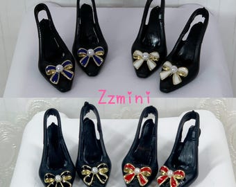May include: Miniature black slingback shoes with pointed toes and decorative bows. Set A features blue and white bows with central pearls. Set B features black and red bows with central pearls. The text Zzmini is visible between the two sets.