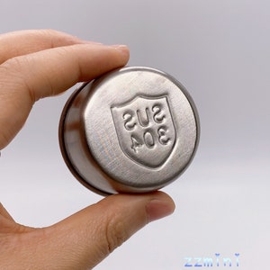 May include: A silver round container with a shield-shaped logo that says "304 SUS" on it.
