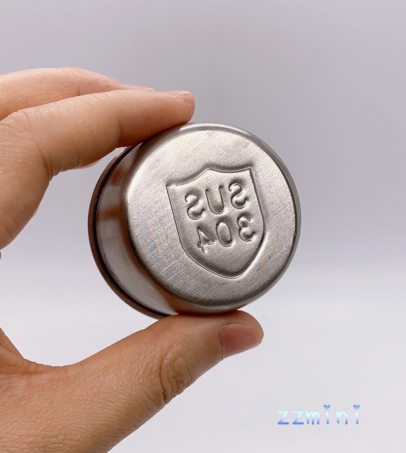 May include: A silver round container with a shield-shaped logo that says "304 SUS" on it.