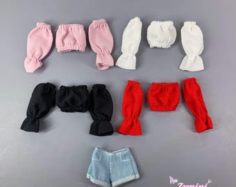 May include: A collection of miniature doll clothing items including four sets of long sleeves and matching tube tops in pink, white, black, and red, plus a pair of light blue denim shorts. The text Zzmini is visible in the bottom right corner.