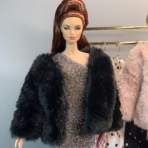 May include: A black faux fur jacket with a silver sparkly dress underneath. The doll is wearing a high bouffant hairstyle.