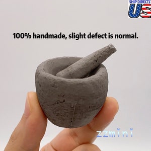 Könnte beinhalten: Ein kleiner, grauer, handgefertigter Mörser und Stößel. Der Mörser ist rund und hat eine raue Textur. Der Stößel ist lang und dünn. 100% handgefertigt, leichte Mängel sind normal.