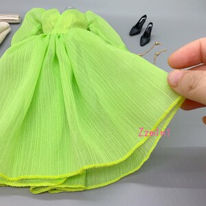 May include: A lime green chiffon dress with a yellow trim. The dress has a gathered waist and a flowing skirt.