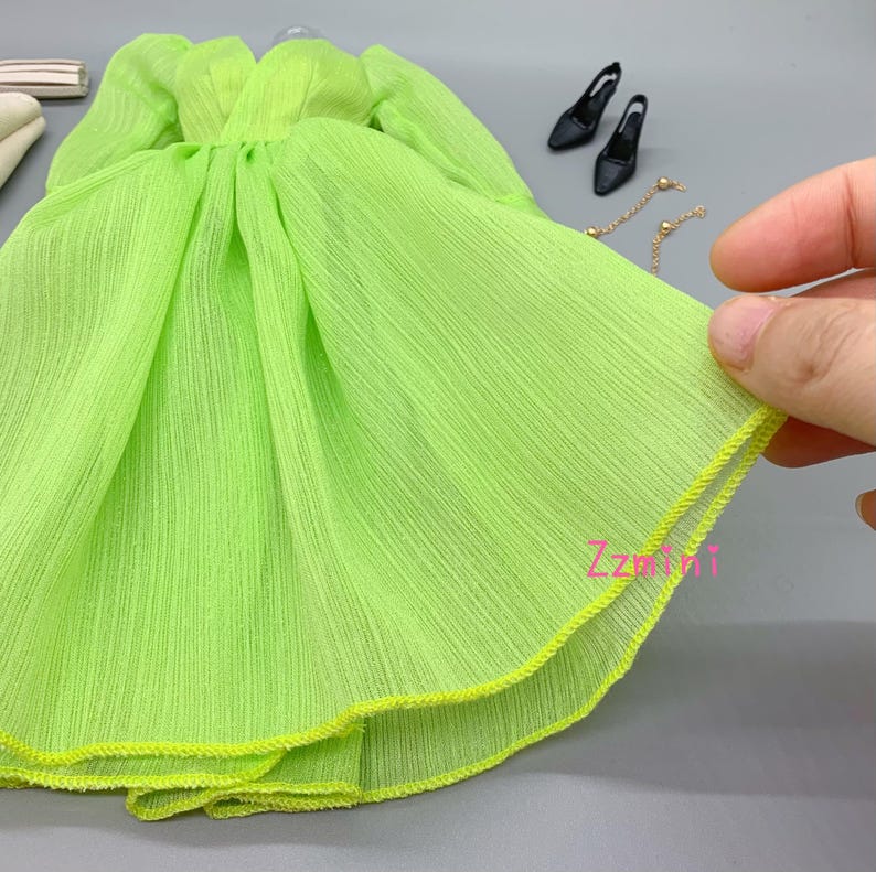 May include: A lime green chiffon dress with a yellow trim. The dress has a gathered waist and a flowing skirt.