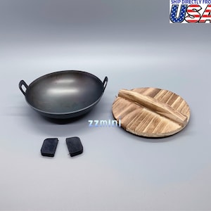 May include: A black metal wok with two handles and a wooden lid. The wok is sitting on a white surface. There are two black rubber pieces next to the wok.