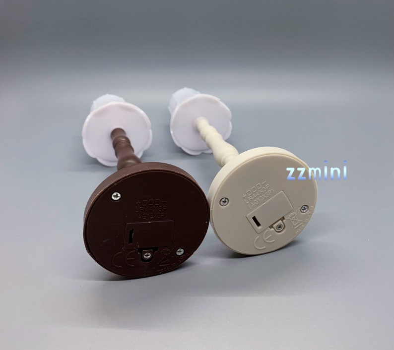 Pu&ograve; includere: Due lampade da tavolo in miniatura con paralumi bianchi e basi marroni e bianche. Le basi hanno un interruttore sul fondo e il testo "TODD - LR14/C - 4.5V DC - 4510X30"