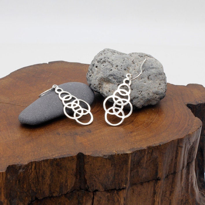 Geometric earrings with intersecting curved lines, 32 millimeters long. Made by Los Sueños de Catalina in solid 925 silver