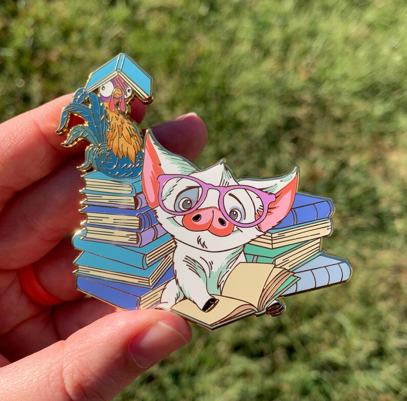Op de afbeelding: Een wit varken met roze bril zit op een stapel kleurrijke boeken en leest een boek. Een haan met rode en gele veren zit bovenop de boeken.