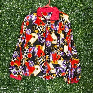 May include: A black, red, white, purple and gold patterned jacket with a zip closure. The jacket has a pink collar and a label that reads "PTN".