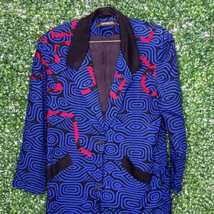 May include: A blue blazer with a black and red abstract pattern. The blazer has a black collar and two pockets. The label on the blazer reads "Carmagnola".