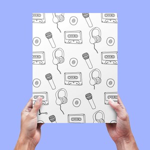 May include: A white sheet of paper with a black and white repeating pattern of cassette tapes, headphones, microphones, and records. The paper is being held by two hands.