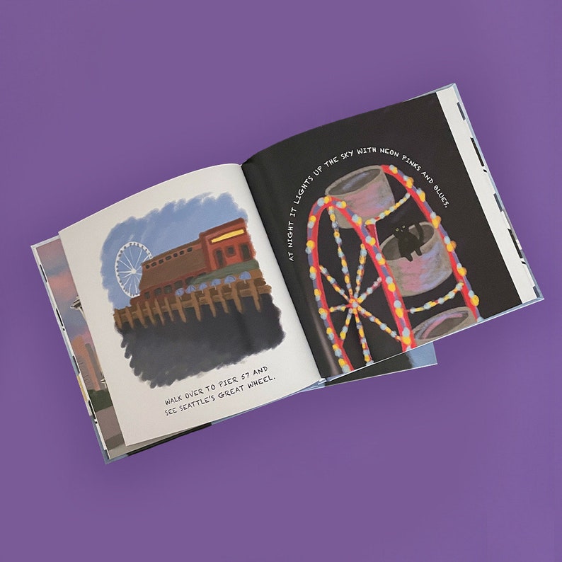 May include: An open children's book with illustrations of Seattle's Great Wheel and Pier 57. The right page shows a Ferris wheel lit with neon pinks and blues against a dark sky. Text reads, "At night it lights up the sky with neon pinks and blues."
