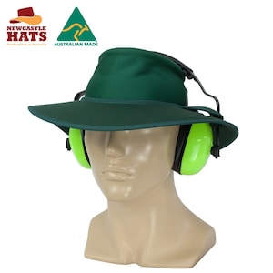 May include: A green wide-brimmed hat with a dark green trim and earmuffs. The hat is made in Australia. "NEWCASTLE HATS handcrafted in Australia" and "AUSTRALIAN MADE" are printed on the hat.