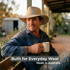 May include: A beige hat with a wide brim is worn by a person. The person is wearing a blue plaid shirt and holding a white mug. The text "Built for Everyday Wear" and "Made in Australia" is displayed.