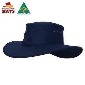 Op de afbeelding: Een marineblauwe hoed met een brede rand, een gestructureerde kroon en een flexibele rand. Aan de zijkant van de kroon zitten drie kleine metalen ventilatiegaatjes. De logo's van Newcastle Hats en Australian Made zijn in de hoek zichtbaar.