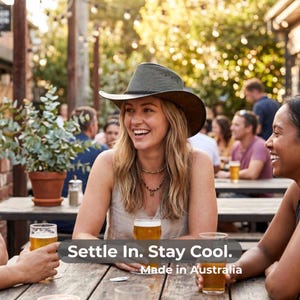 May include: A woman wearing a brown and green hat smiles while sitting at a wooden table with friends. The image includes the text "Settle In. Stay Cool. Made in Australia."