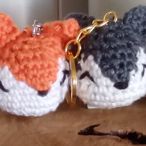 May include: Five crocheted animal keychains. The keychains are a deer, fox, wolf, penguin, and a bird. The keychains are all white with different colored accents. The keychains are all about 3 inches tall.