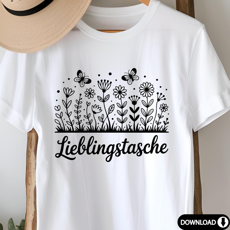 May include: White t-shirt featuring a black floral design with butterflies and the German text "Lieblingstasche". The design includes various flowers and foliage.