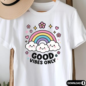 May include: White t-shirt with a rainbow, clouds, and flowers graphic. The text "GOOD VIBES ONLY" is printed in black below the graphic.