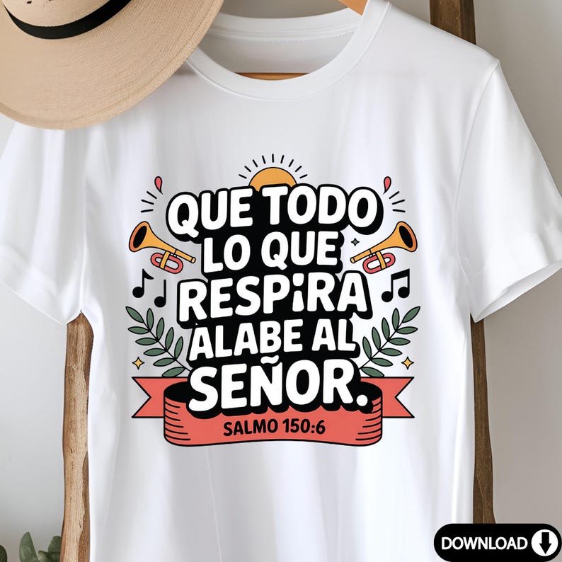 May include: White t-shirt featuring the Spanish text "QUE TODO LO QUE RESPIRA ALABE AL SE&Ntilde;OR" with decorative elements including musical notes, trumpets, and a sun. The text is above a red banner with "SALMO 150:6".