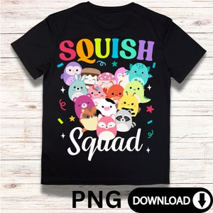 Pode incluir: Camiseta preta com um gráfico arco-íris de vários squishmallows de desenhos animados. O texto "SQUISH Squad" está escrito em branco abaixo do gráfico.