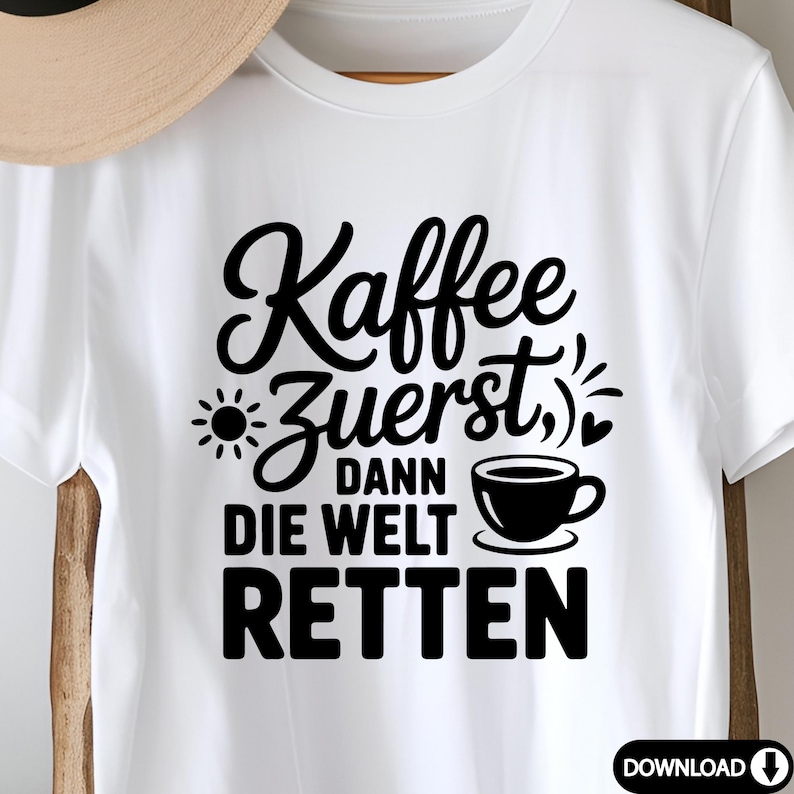 Puede incluir: Camiseta blanca con la frase en negro "Kaffee Zuerst, dann die Welt retten". El dise&ntilde;o incluye un sol, una taza de caf&eacute; y corazones. Una camiseta informal para los amantes del caf&eacute;.