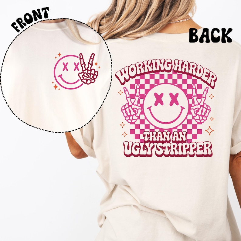 Peut inclure: T-shirt blanc avec un smiley rose aux yeux crois&eacute;s et des mains en signe de paix sur le devant et le texte "WORKING HARDER THAN AN UGLY STRIPPER" avec un smiley rose aux yeux crois&eacute;s et des mains en signe de paix au dos.