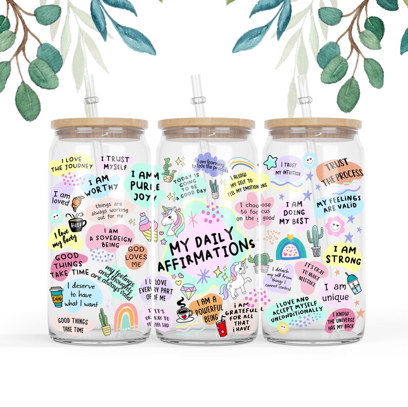 Op de afbeelding: Drie glazen waterflessen met bamboe deksels en rietjes. Elke fles is versierd met kleurrijke stickers en positieve affirmaties. De stickers bevatten eenhoorns, regenbogen, cactussen en andere fantasierijke ontwerpen. De tekst op de stickers bevat zinnen als "Ik ben het waard", "Ik doe mijn best" en "Mijn dagelijkse affirmaties".