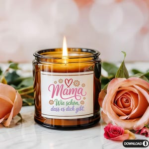 May include: A lit candle in a brown glass jar with a white label. The label has the word "Mama" in pink script, with a heart and flower accents. The text "Wie sch&ouml;n, dass es dich gibt" is also on the label. The candle is surrounded by pink roses.