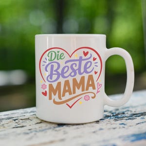 May include: White ceramic mug with a large handle. The mug features the German text "Die Beste Mama" in a heart-shaped design with red, purple, green, and brown colors. Small floral and heart accents surround the text.
