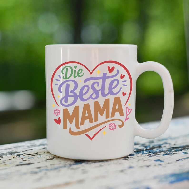 May include: White ceramic mug with a large handle. The mug features the German text "Die Beste Mama" in a heart-shaped design with red, purple, green, and brown colors. Small floral and heart accents surround the text.