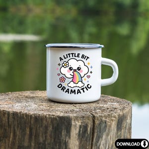 May include: White enamel mug with a black rim and handle. The mug features a cartoon cloud with a rainbow coming out of its mouth. The text "A little bit dramatic" is printed on the mug.