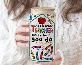 May include: White tumbler with a bamboo lid and a straw. The tumbler has a colorful design with the text "TEACHER thanks for all you do" and a red apple with a smiling face.