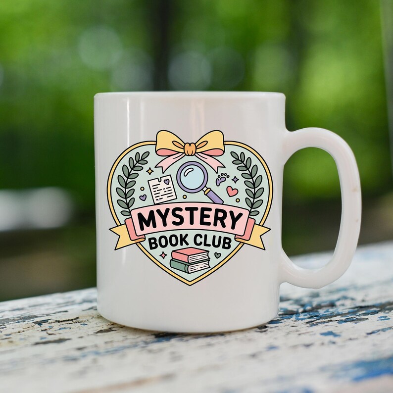 May include: White ceramic mug featuring a heart-shaped design with a magnifying glass, books, and the text "MYSTERY BOOK CLUB." The design includes a bow and decorative elements in pastel colors. The mug has a large handle.