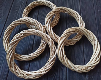 May include: Four natural woven wreaths made of willow branches. The wreaths are all the same size and are arranged in a circle on a dark wooden surface.