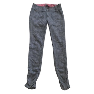 Op de afbeelding: Grijze tweed broek met een getailleerde snit. De broek heeft een knoop- en ritssluiting, riemlussen en een roze voering met patroon. De pijpen hebben een gerimpeld detail bij de enkels.