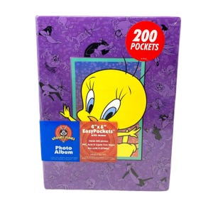 May include: A purple Looney Tunes photo album featuring Tweety Bird. The album has 200 pockets for 4" x 6" photos. The cover is decorated with Looney Tunes characters.